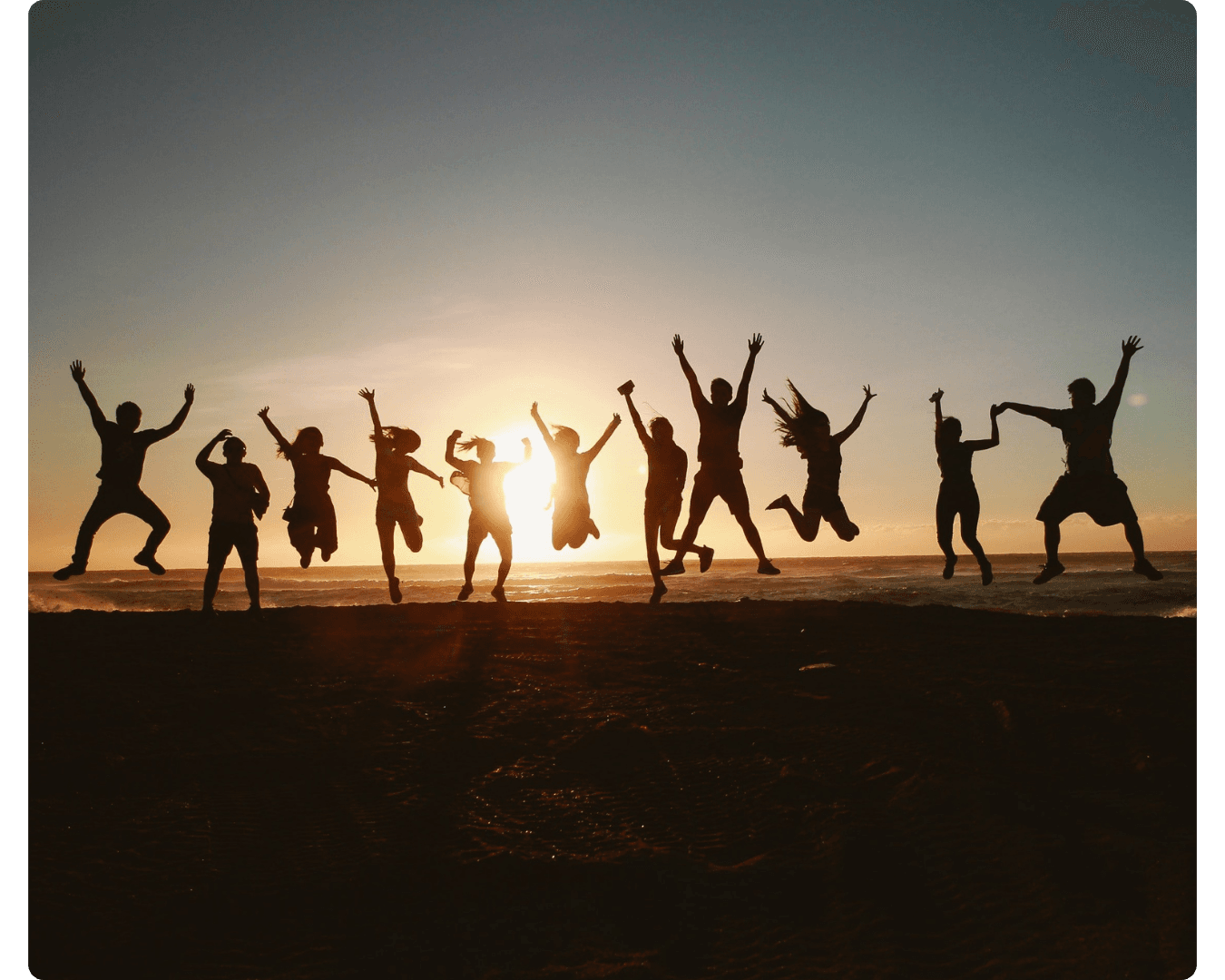Group of people cheering at sunset
