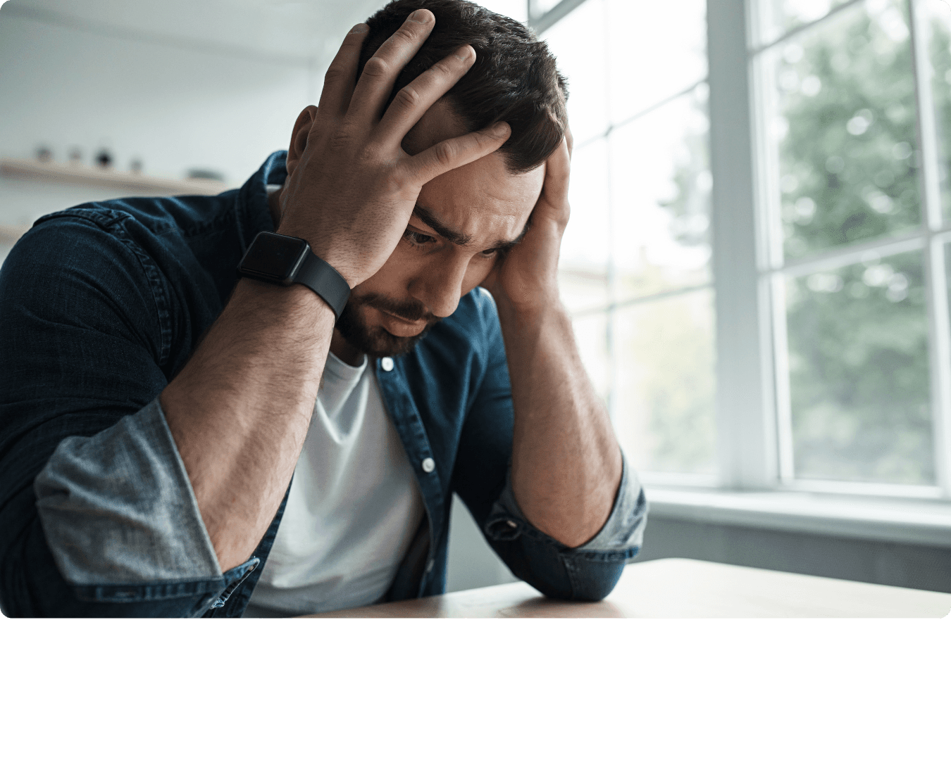 Person sitting at a desk with their head in their hands