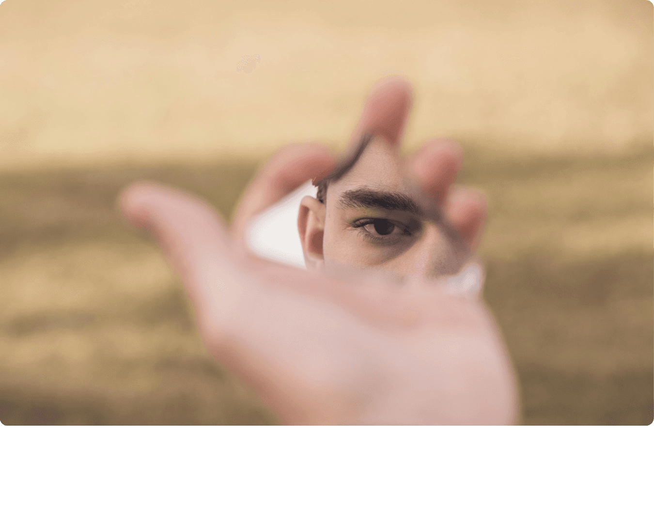 Hand holding a mirror shard reflecting an eye