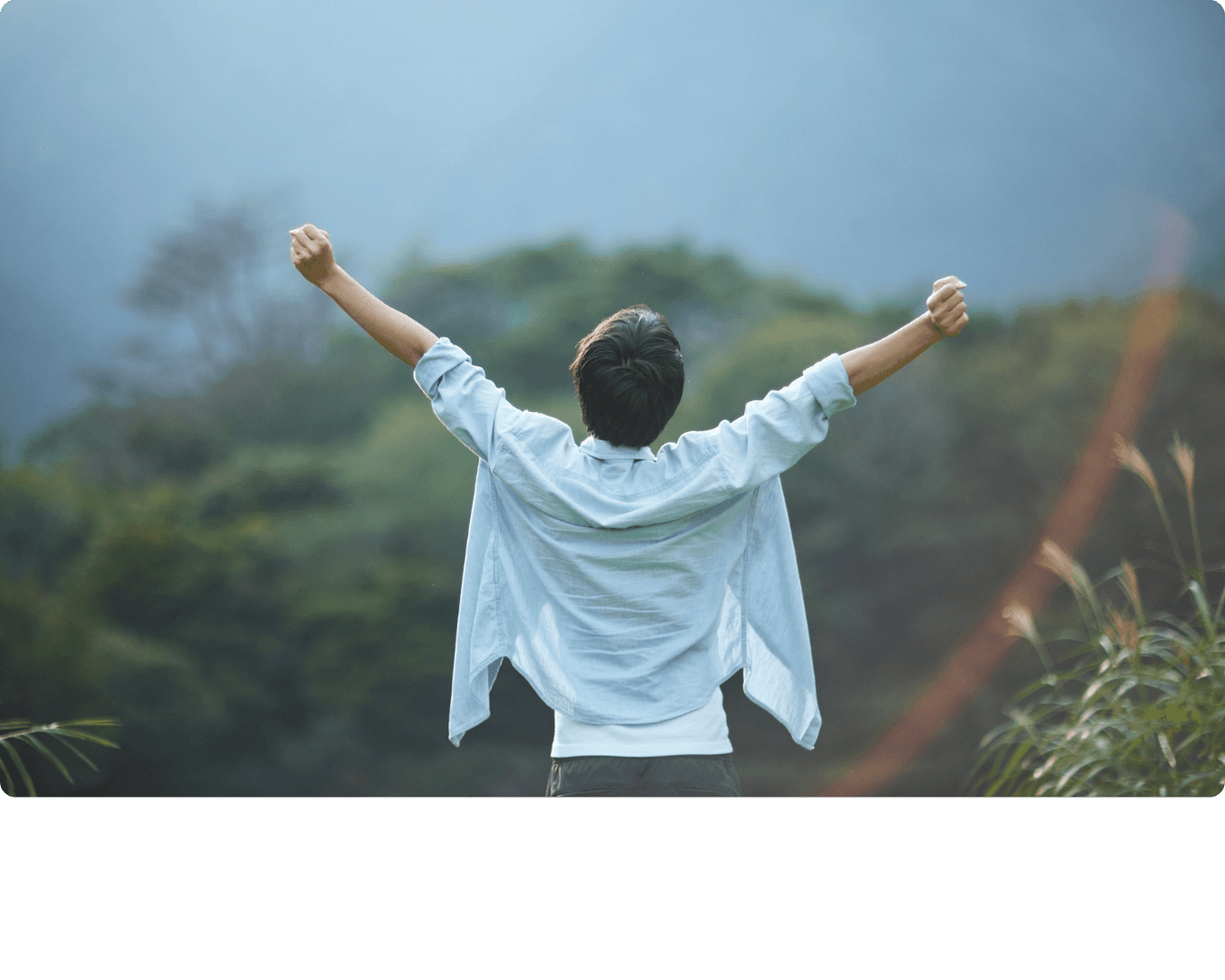 Person with arms outstretched overlooking a misty landscape